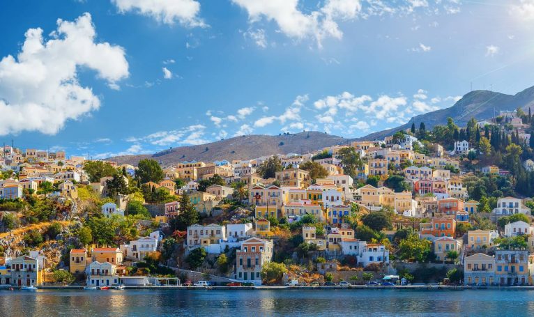 Panoramic shot of the Harbour at Symi Greece with a traditional fishing boat in the foreground. Greece Europe.
